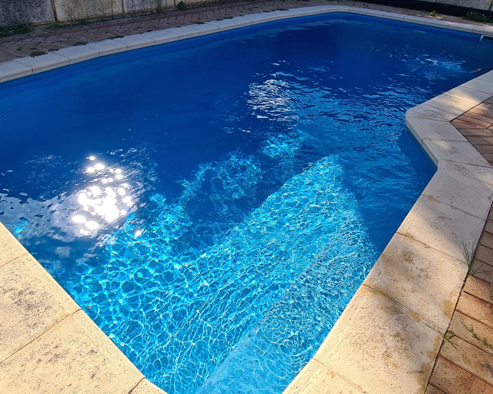 Rectangular pool with clear blue water and concrete edges.